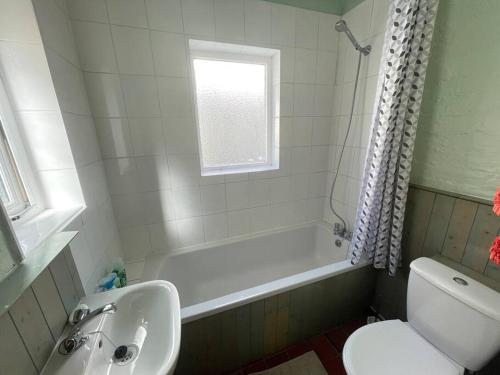 y baño con bañera, aseo y lavamanos. en Lovely 2 bedroom house overlooking park, Free parking en Belfast