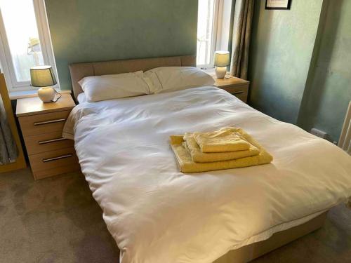 um quarto com uma cama branca com duas toalhas em Lovely 2 bedroom house overlooking park, Free parking em Belfast