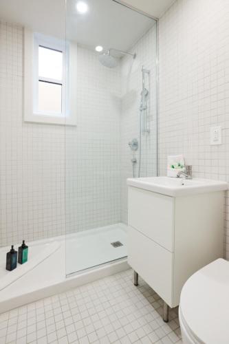 a white bathroom with a tub and a toilet and a sink at Urban Gem in Le Plateau by Denstays in Montréal