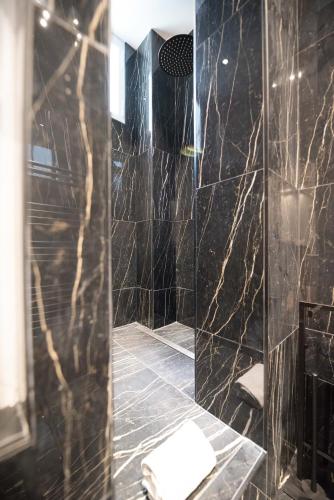 La salle de bains noire est pourvue d'une douche avec du carrelage noir. dans l'établissement Lovely Flat in the marais, à Paris