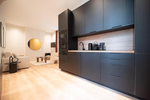 une cuisine avec des armoires noires et un salon dans l'établissement Lovely Flat in the marais, à Paris