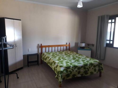 a bedroom with a bed with a green blanket at Casa privada - Balneário Gaivota-SC 150 metros do mar in Sombrio