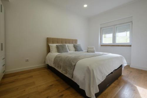 a bedroom with a large bed in a white room at Apartamento T3 em Lisboa/ Queluz in Queluz