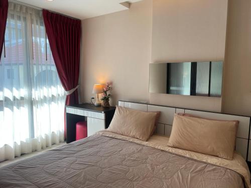 a bedroom with a large bed and a window at The Chezz by Apple & Frank in Pattaya Central