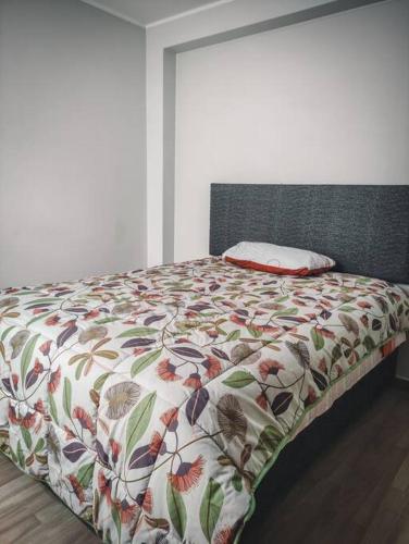 a bed with a floral comforter in a bedroom at Departamento a 5 minutos del centro de Huancayo in Huancayo