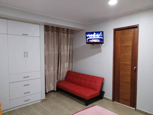 un divano rosso in una stanza con TV a parete di Departamento a 5 minutos del centro de Huancayo a Huancayo