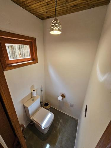 a bathroom with a white toilet and a window at Tawa Caraíva in Caraíva