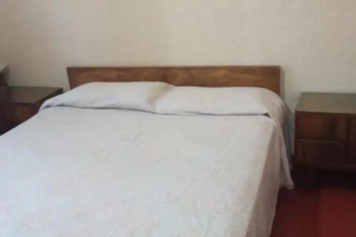 1 dormitorio con 1 cama blanca y 2 mesitas de noche en Departamento a 200mts de la playa en Miramar