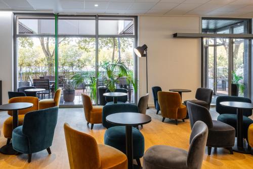 a waiting room with tables and chairs and windows at ibis Styles Paris Saint Denis Pleyel in Saint-Denis