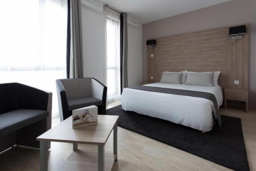 a bedroom with a bed and a chair and a table at Twenty Business Flats Lille Grand Stade in Villeneuve d'Ascq