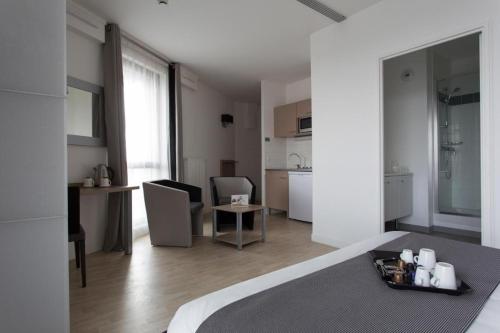 een witte kamer met een bed en een keuken bij Twenty Business Flats Lille Grand Stade in Villeneuve d'Ascq