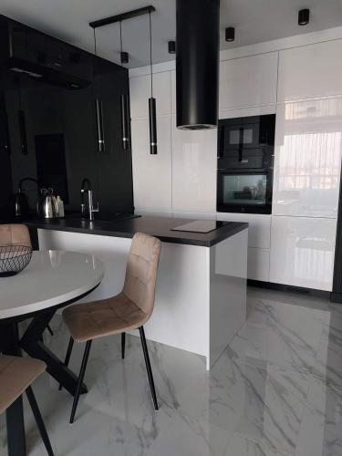 a kitchen with black and white cabinets and a table and chairs at Westin House Black in Kołobrzeg