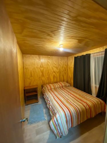 ein kleines Bett in einem kleinen Zimmer mit Fenster in der Unterkunft Cabaña Los Ulmos in Castro