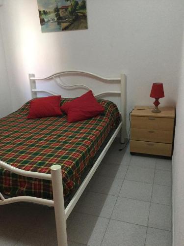 a bedroom with a bed with red pillows and a night stand at Casinhas de Alfenim in Sesimbra