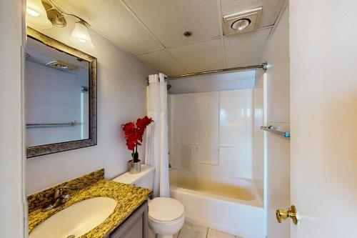 a bathroom with a sink and a toilet and a mirror at Marigot Beach 510 in Ocean City