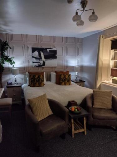 a hotel room with a bed and two chairs at The Crown Inn - Rooms in Keynsham