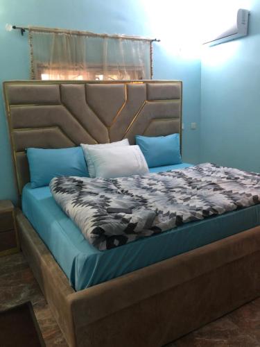 uma cama num quarto com uma parede azul em Dazzle Hotels and Apartments Riverpark em Rubuchi