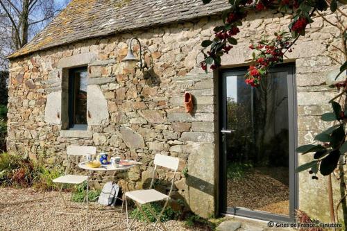 a stone building with a table and chairs in front of it at Gîte chaleureux à 3km des plages in Guimaëc