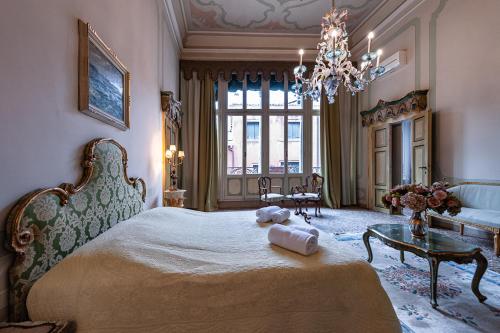 una camera con un grande letto e un lampadario a braccio di Appartamento Duodo o Barbarigo a Venezia