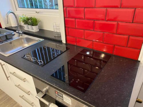 uma cozinha com um lavatório e uma parede de azulejos vermelhos em Spacious 4 Bedroom Townhouse em Leeds