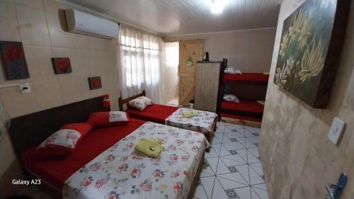 a bedroom with two beds with red sheets at Pousada Leher in São Gabriel
