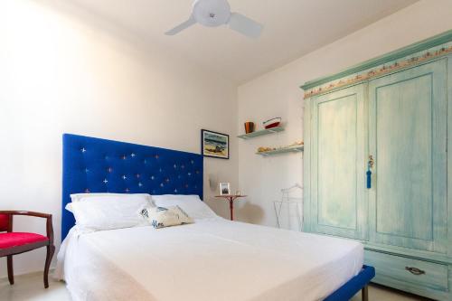 een slaapkamer met een bed met een blauw hoofdeinde en een rode stoel bij Casa Cuore di Nonna in Savelletri di Fasano