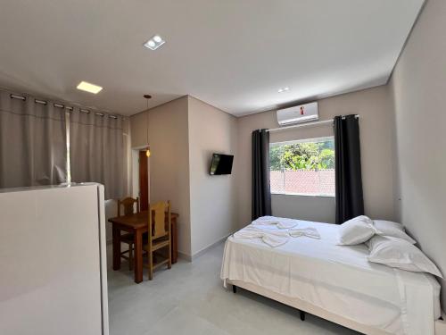 a bedroom with a bed and a window and a table at Loft Juquehy in São Sebastião