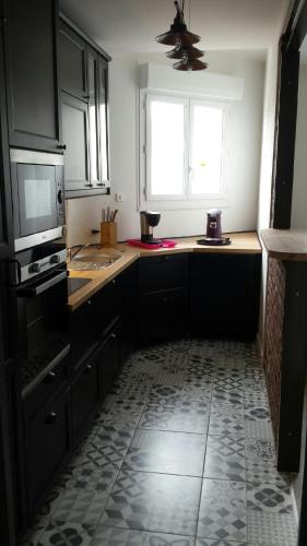 Il comprend une cuisine avec des placards noirs et du carrelage. dans l'établissement Villa loucontou, à Fort-Mahon-Plage