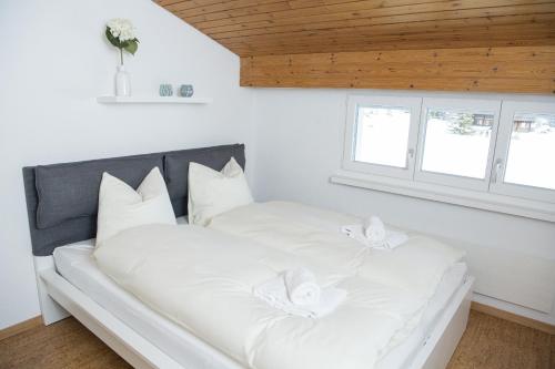 1 cama blanca con almohadas blancas en una habitación en Ferienwohnung Canols für 6 Personen Valbella-Lenzerheide, en Valbella