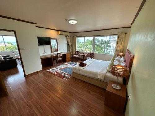 1 dormitorio con 1 cama y sala de estar con escritorio. en Thipurai Beach Hotel en Hua Hin