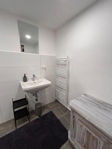 Baño blanco con lavabo y silla en Haus Grimmingblick en Zlem