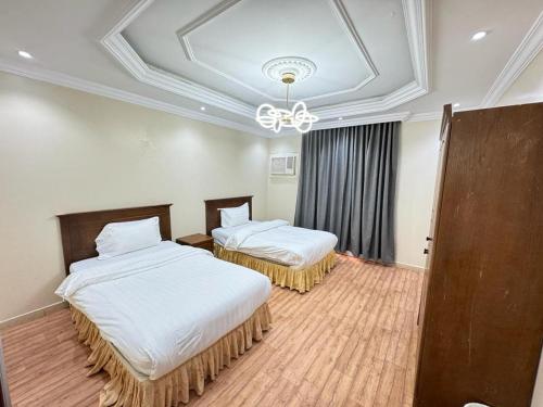 a room with two beds and a chandelier at الاصايل 1-طريق الاربعين in Al-Safa