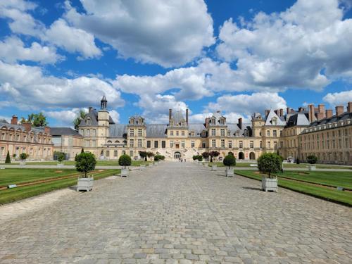 a large castle with a cobblestone street in front of it at Mobil Home en Camping proche Paris en Ile de France in Saint-Chéron