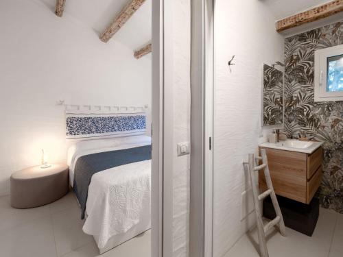 - une chambre blanche avec un lit et un lavabo dans l'établissement Appartamento Acquamarina, à Porto Rotondo