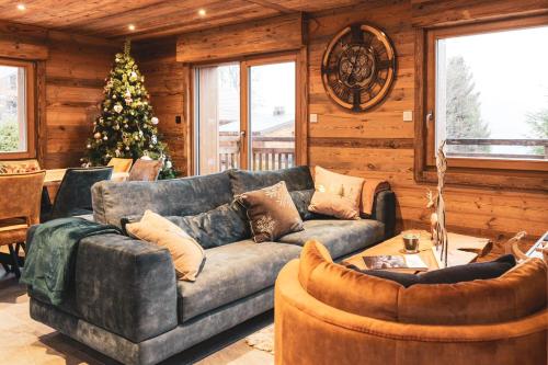 a living room with a couch and a christmas tree at Chalet Louléa - Luxueux, au calme avec Spa in Xonrupt-Longemer