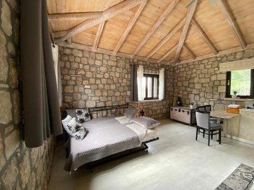 a bedroom with a bed and a stone wall at AGROTOPIA Guesthouses in Theologos