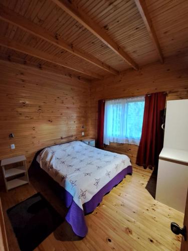 a bedroom with a bed in a wooden room at Cabañas M&R Lago Ranco in Lago Ranco