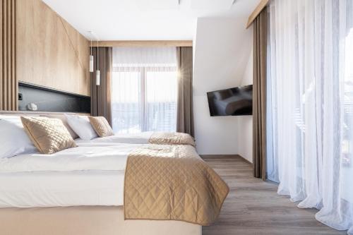 a bedroom with a bed and a large window at Apartamenty Krokusowa Dolina in Kościelisko