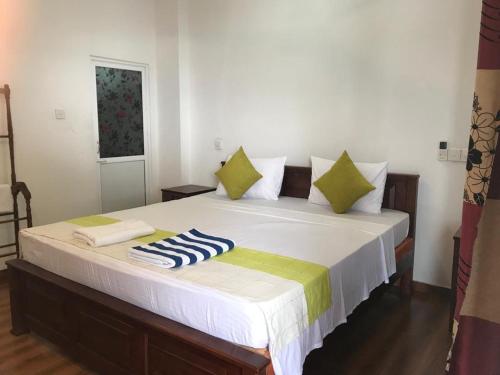 Tamaro Beach Resort في هيكادوا: غرفة نوم بسرير كبير ومخدات خضراء وبيضاء