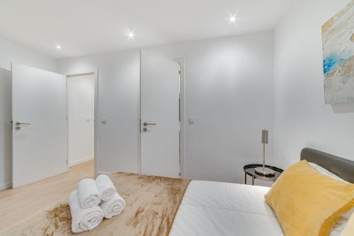 a bedroom with white walls and a bed with towels at Duplex Apartment near Belém in Lisbon
