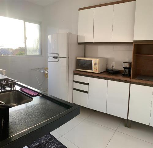La cuisine est équipée d'un réfrigérateur blanc et d'un évier. dans l'établissement Apartamento Temporada Mobiliado Proximo a Praia, à Vila Velha