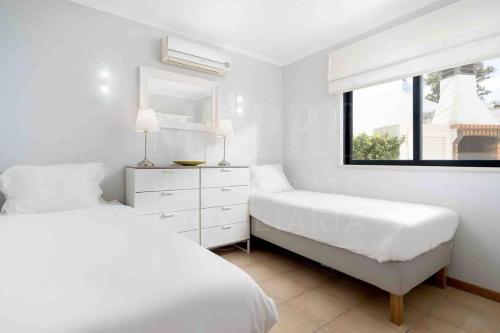 a white bedroom with two beds and a window at Stunning 3 bed Villa in Vale do Lobo with Resort Membership 3 mins From Beach and Golf in Loulé