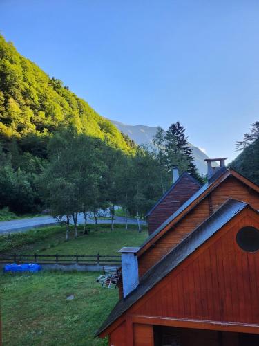 a red house with a mountain in the background at ELLA in Aragnouet