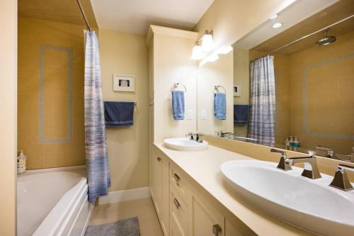 ein Badezimmer mit zwei Waschbecken, einer Badewanne und einem Spiegel in der Unterkunft Vine & Balsam in Vancouver