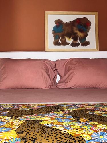 a bed with two pillows and a painting of a leopard at IANUA Casa per Viaggiatori in Astypalaia