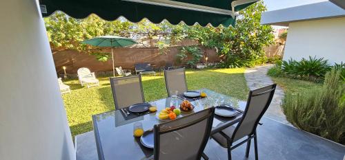 una mesa de comedor con sillas y una sombrilla en el patio trasero en Paradise Garden San Agustin, en San Agustín