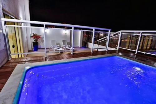 una gran piscina azul en un balcón por la noche en Flat Particular - próx Assembleia Leg MT, en Cuiabá