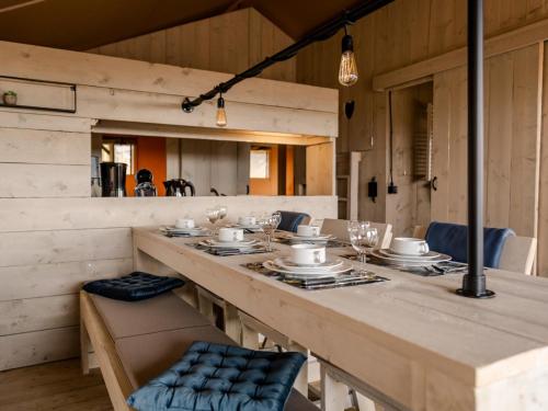 Glamping Lodge في Westerland: طاولة خشبية طويلة عليها كراسي وأطباق