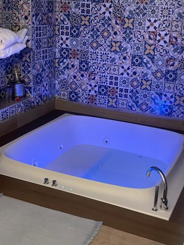 La salle de bains est pourvue d'une baignoire et de carrelage bleu. dans l'établissement San Nicola Suite & mini apartment, à Sorrente