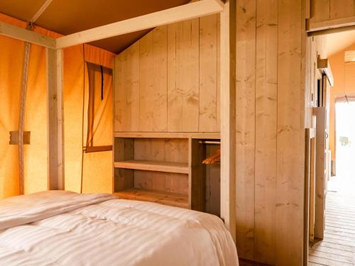 Glamping Lodge في Westerland: غرفة نوم بسرير وجدران خشبية